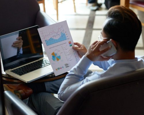 shoulder-view-man-multitasking-reviewing-financial-document-having-telephone-chat (1)